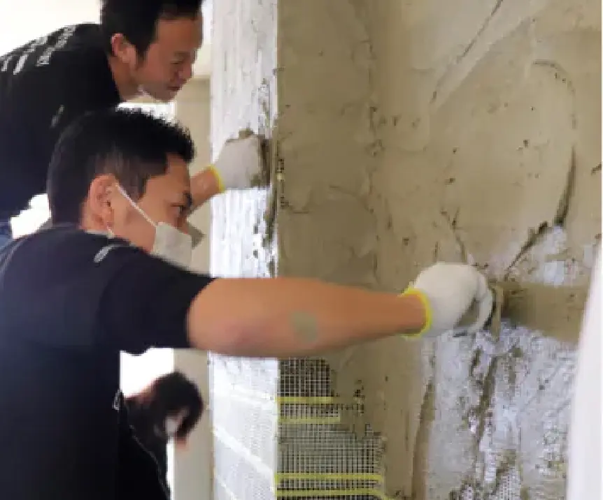 職人が壁に下地を塗っている
